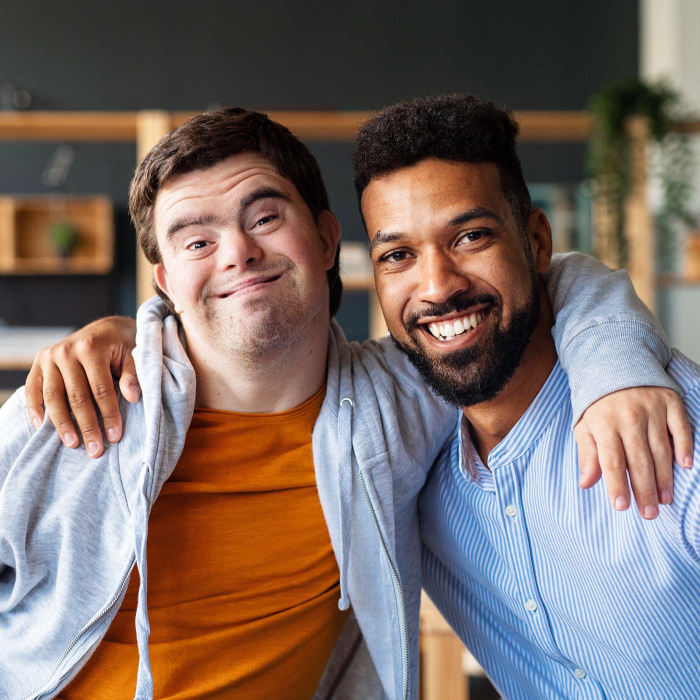 confident young man with autism with his mentor smiling with arms on each others shoulders
