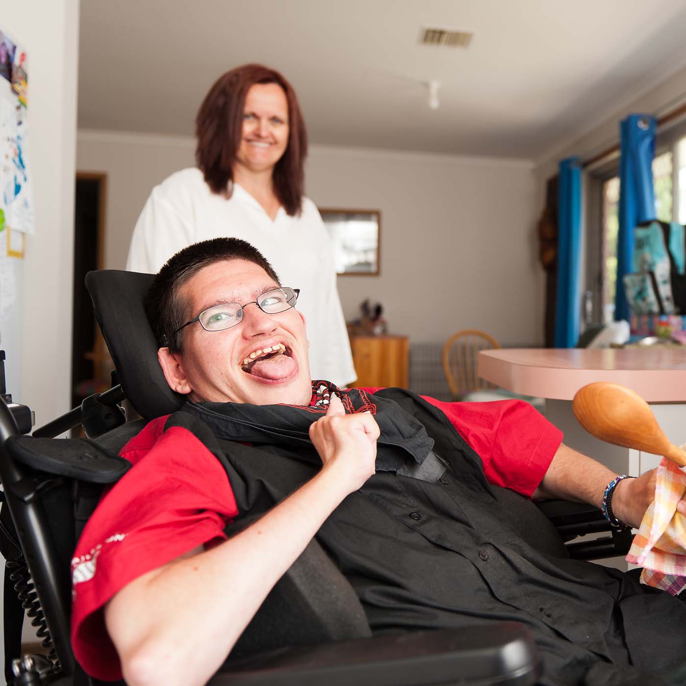 young man with intellectual and physical disability smiling and loving life in his group home