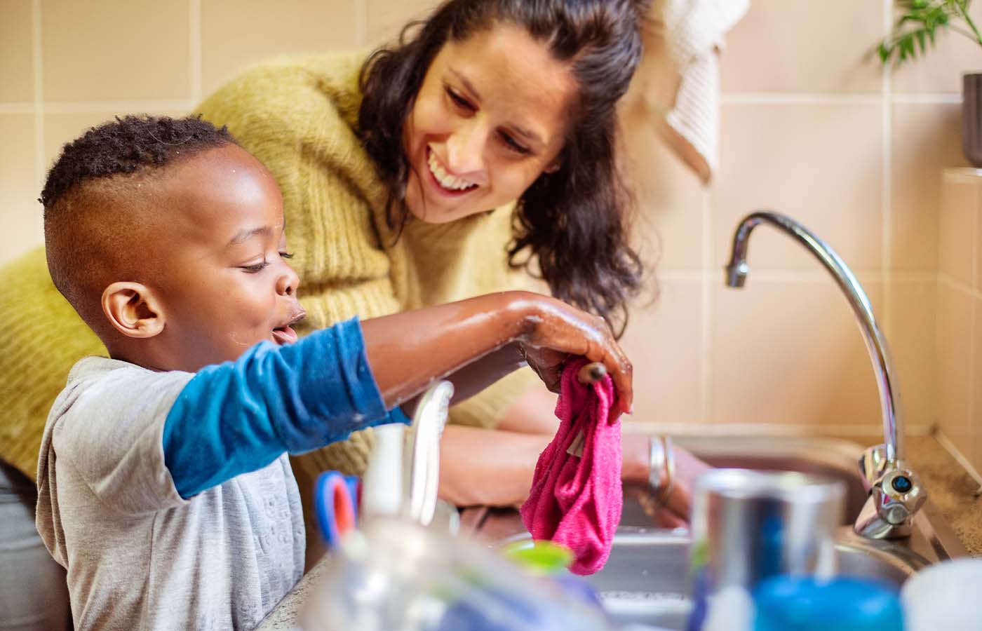 young boy helping his foster mom wash dishes