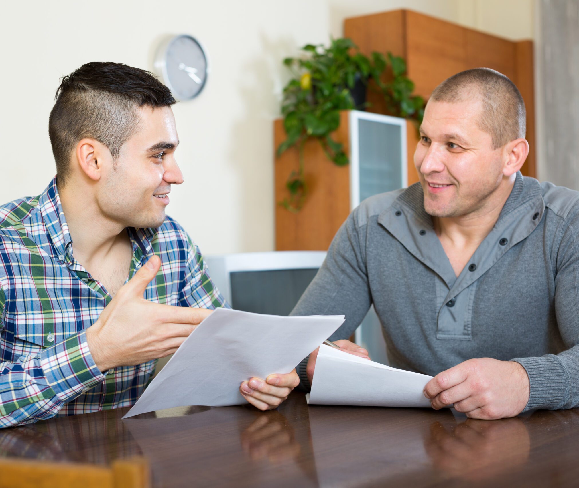 two men talking and holding paperwork